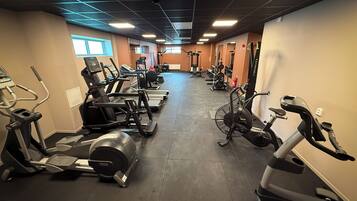Une salle de sport équipée de plusieurs tapis de course, de vélos d’appartement et d’appareils de musculation.