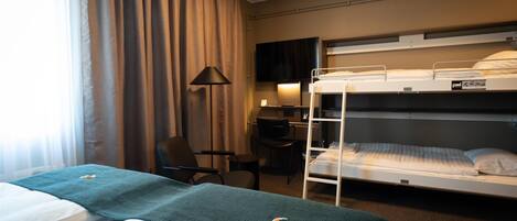 Habitación de hotel con dos camas, un escritorio, una silla, un televisor y una ventana con cortinas.
