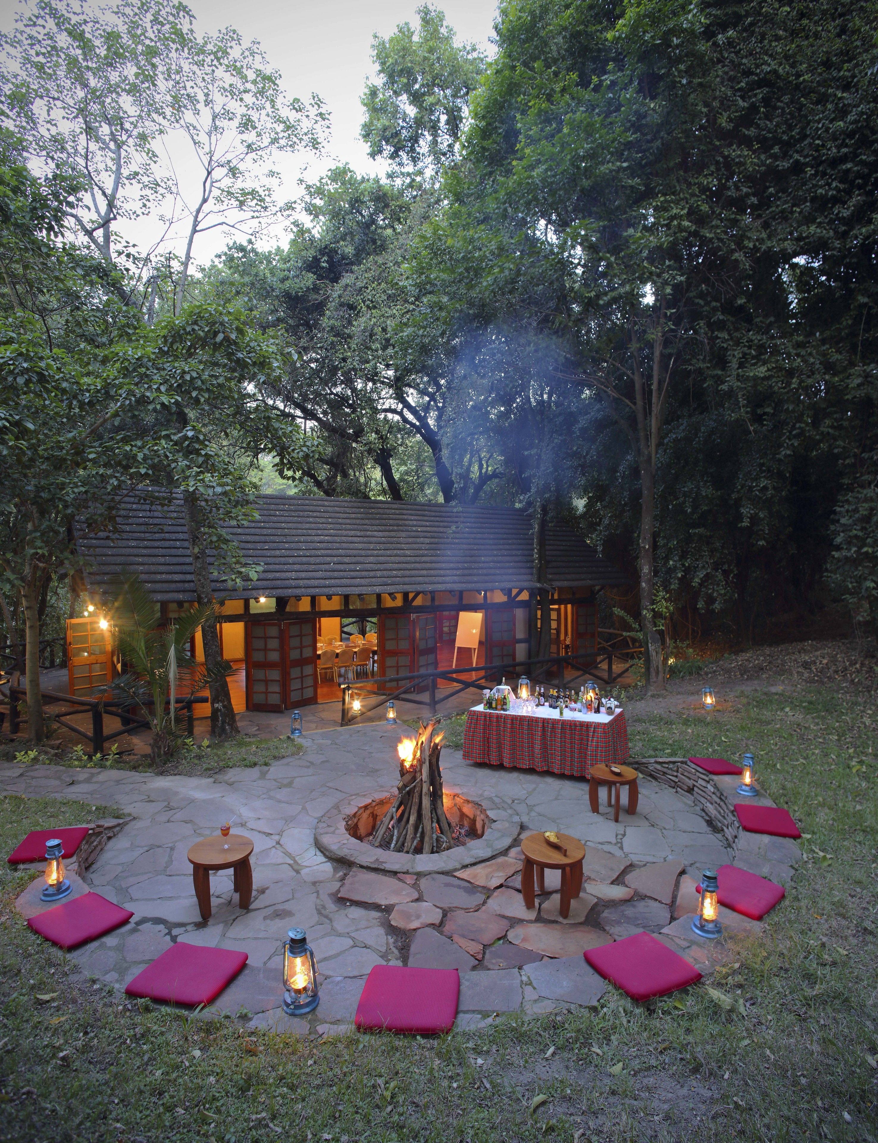 An outdoor patio area with a fire pit, seating, and a table set for dining.