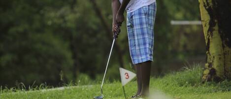 Una persona en un campo de golf junto a un marcador de bandera.