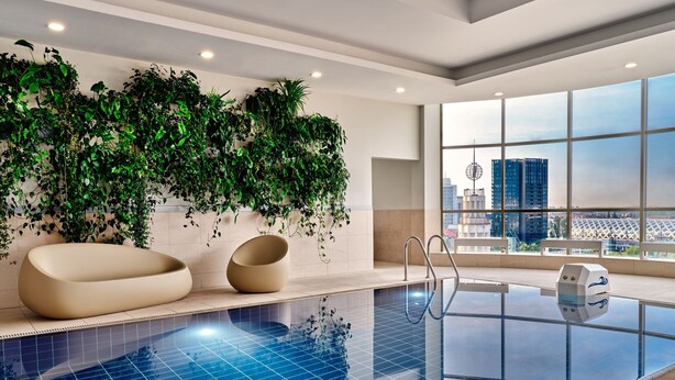 Ein moderner, überdachter Pool mit freiem Blick auf die Skyline der Stadt durch große Fenster.