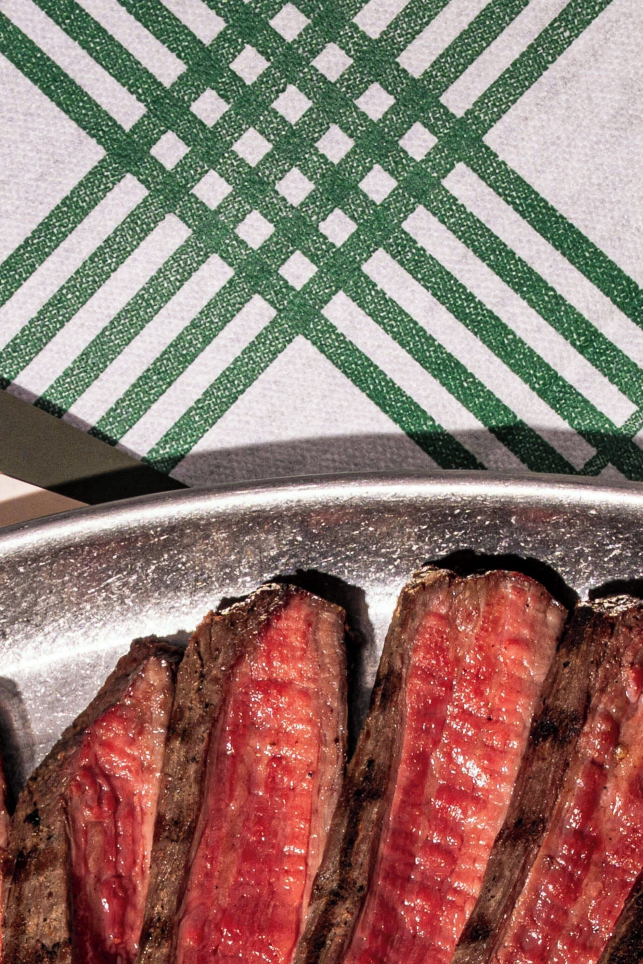 Et nærbillede af en bøf med grillmønster, liggende på en metalbakke.
