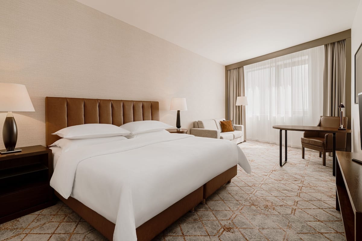 Ein Hotelzimmer mit einem großen Bett, einem Schreibtisch, einem Stuhl und einem Fernseher.