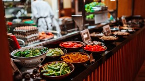 Ein Buffet mit verschiedenen Speisen, darunter Salate, Gemüse und Fleisch.