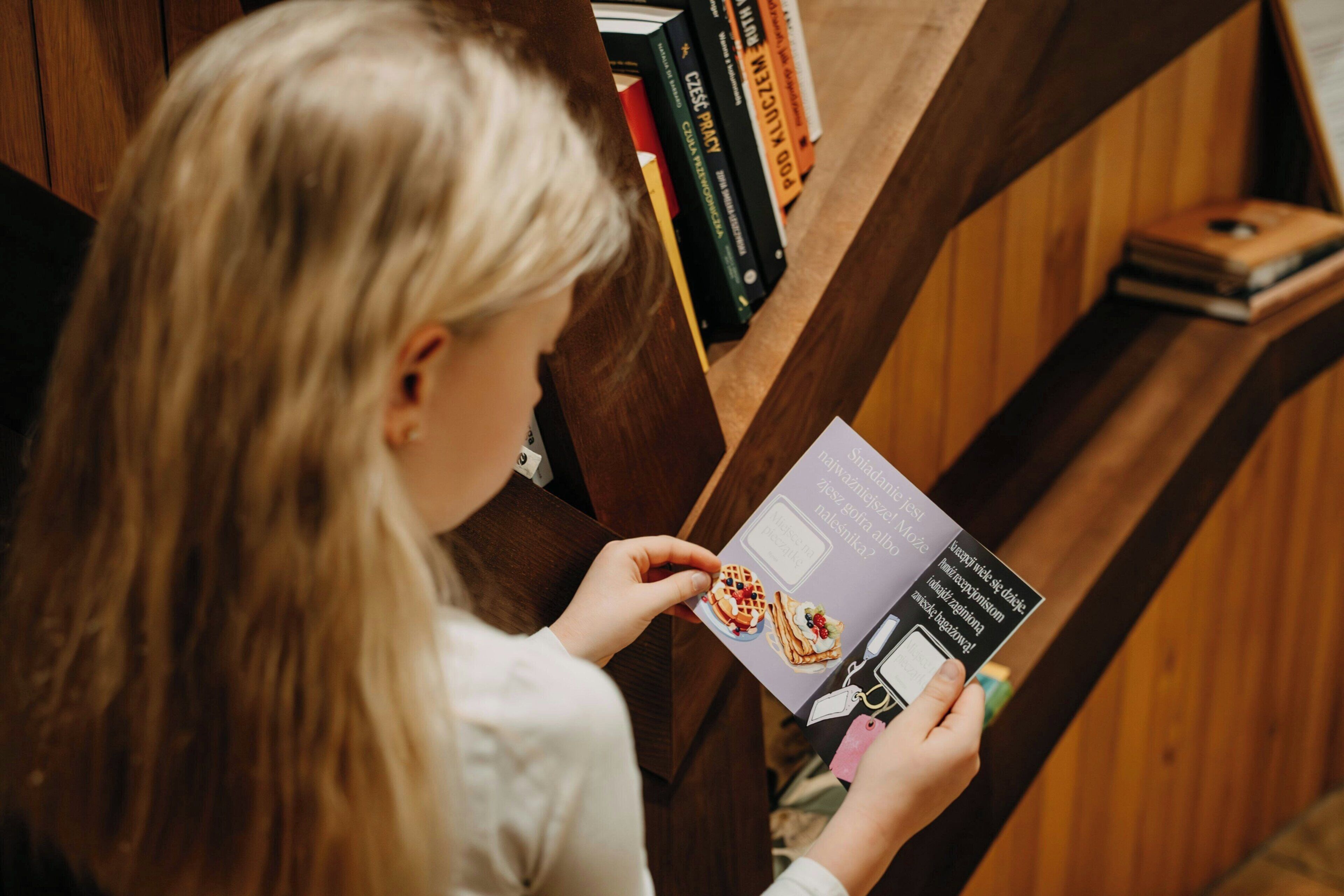 Una persona leyendo un libro en una habitación con estanterías de madera.