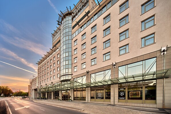 A modern hotel with a glass facade, multiple floors, and a prominent entrance with a glass canopy.
