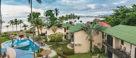 A resort with a swimming pool, palm trees, and a view of the ocean.