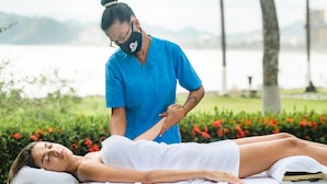 A person receiving a massage outdoors with a lake and greenery in the background. - Hotel Club Del Mar (Jacó)