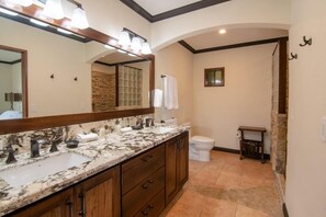 Une salle de bain avec un lavabo en marbre, des meubles en bois, un grand miroir et des toilettes.