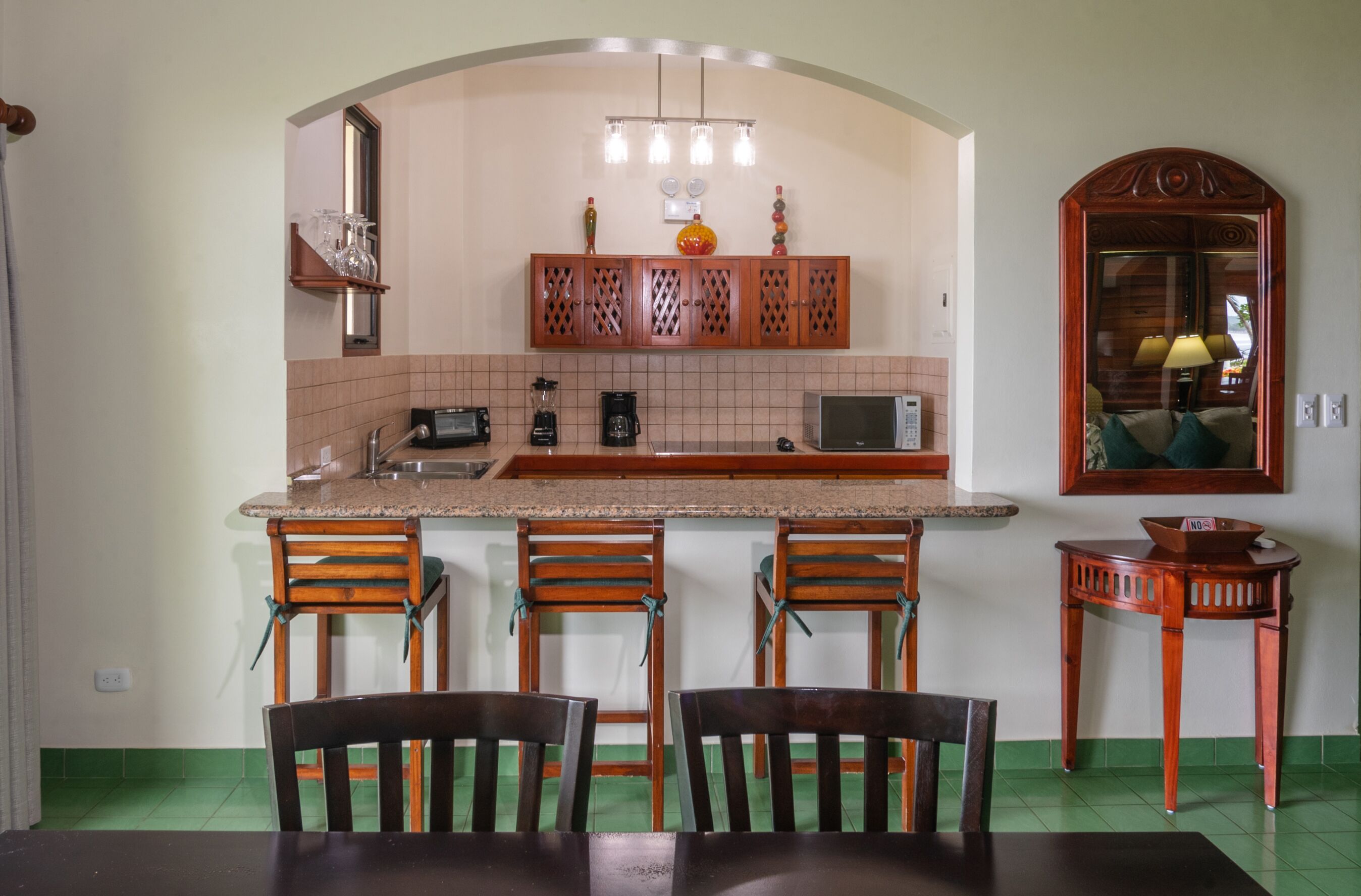 A kitchen with a central island, bar stools, and a dining table with chairs.