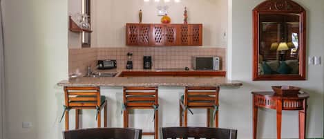 A kitchen with a central island, bar stools, and a dining table with chairs.