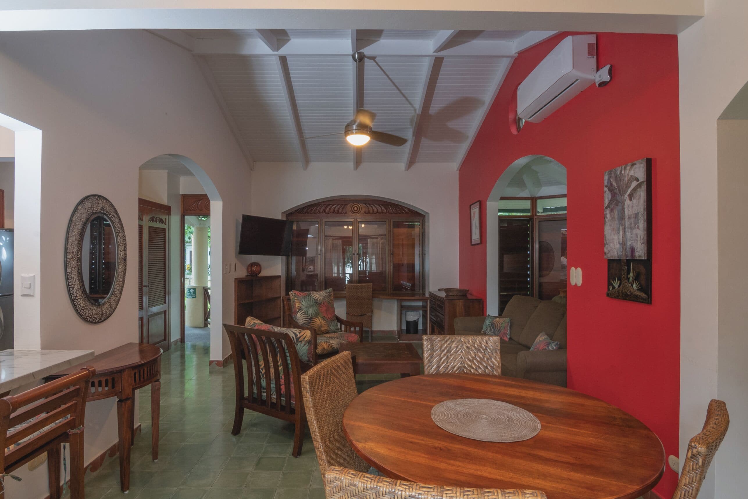 Un salón amplio con mesa de comedor, asientos cómodos y una pared de acento roja.