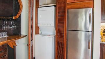 Una cocina compacta con lavadora y secadora integradas, muebles de madera y un refrigerador de acero inoxidable.