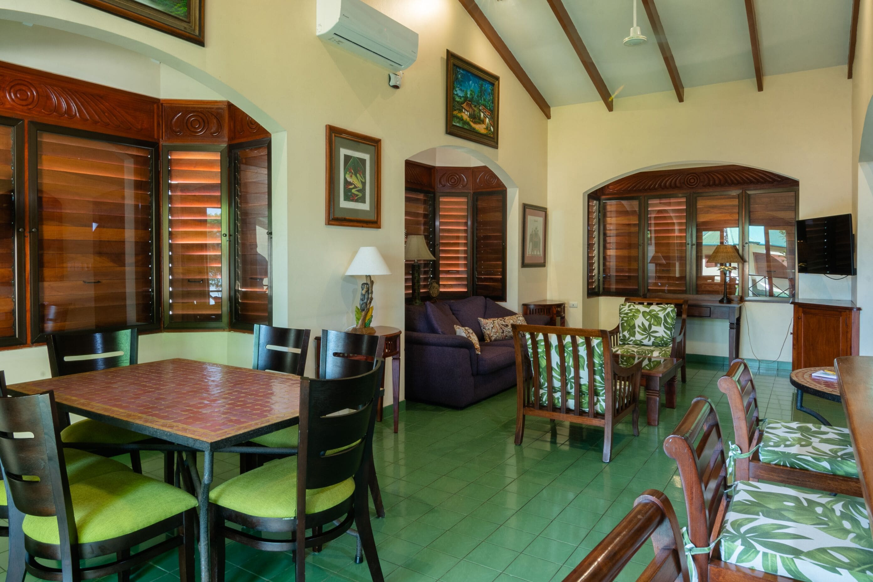 A spacious living area with a dining table, chairs, a sofa, and a kitchen area.