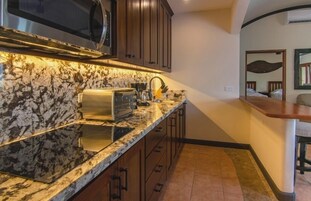 Una cocina con encimera de granito, microondas integrado y armarios de madera.