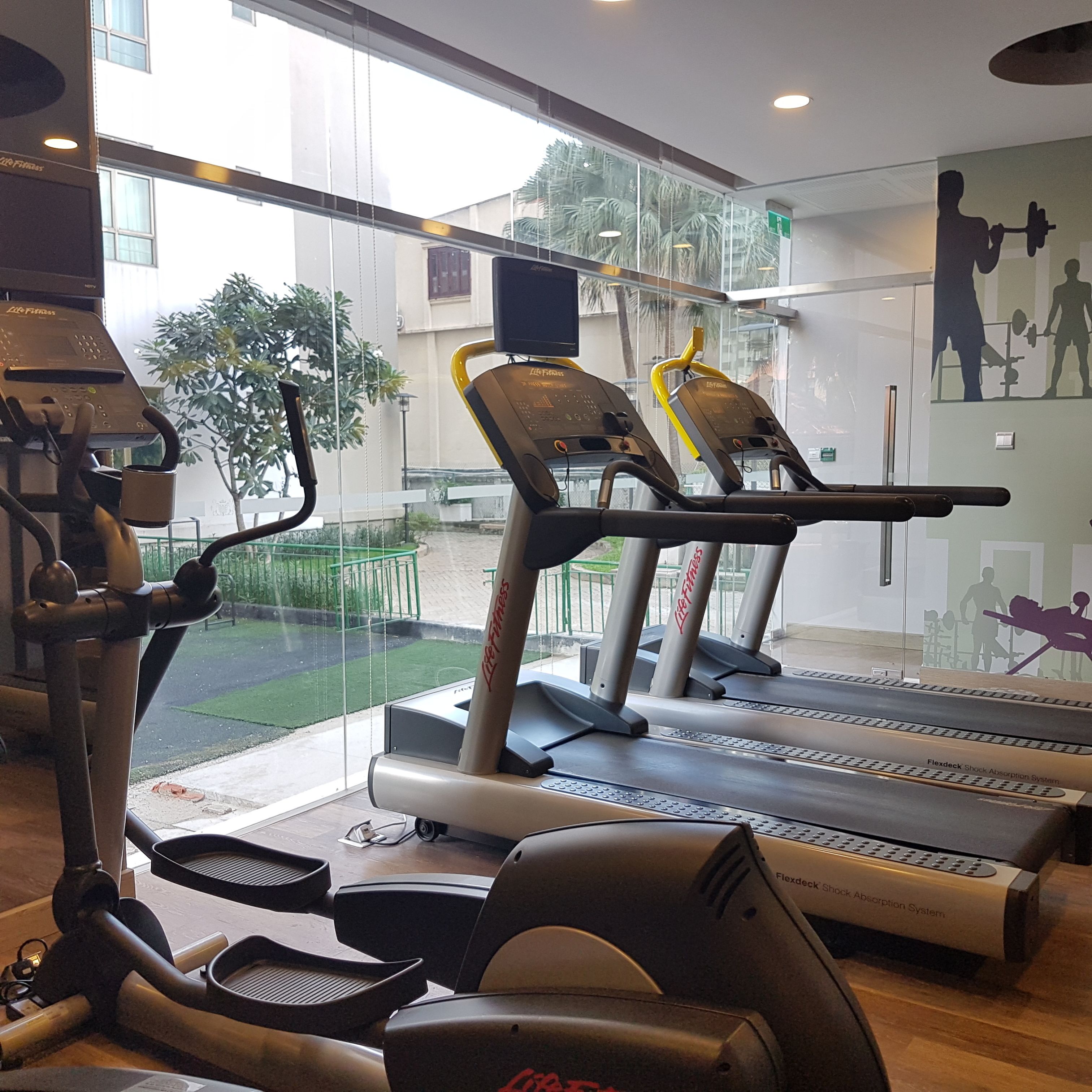 Un gimnasio con cintas de correr, una bicicleta estática y una máquina de remo.