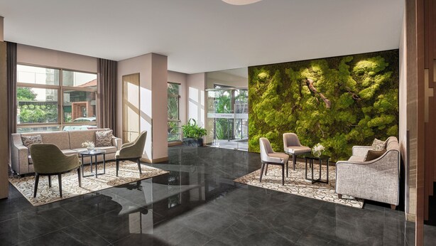A modern lobby with a green moss wall, seating area, and large windows. - Somerset Ho Chi Minh City (Ho Chi Minh City)