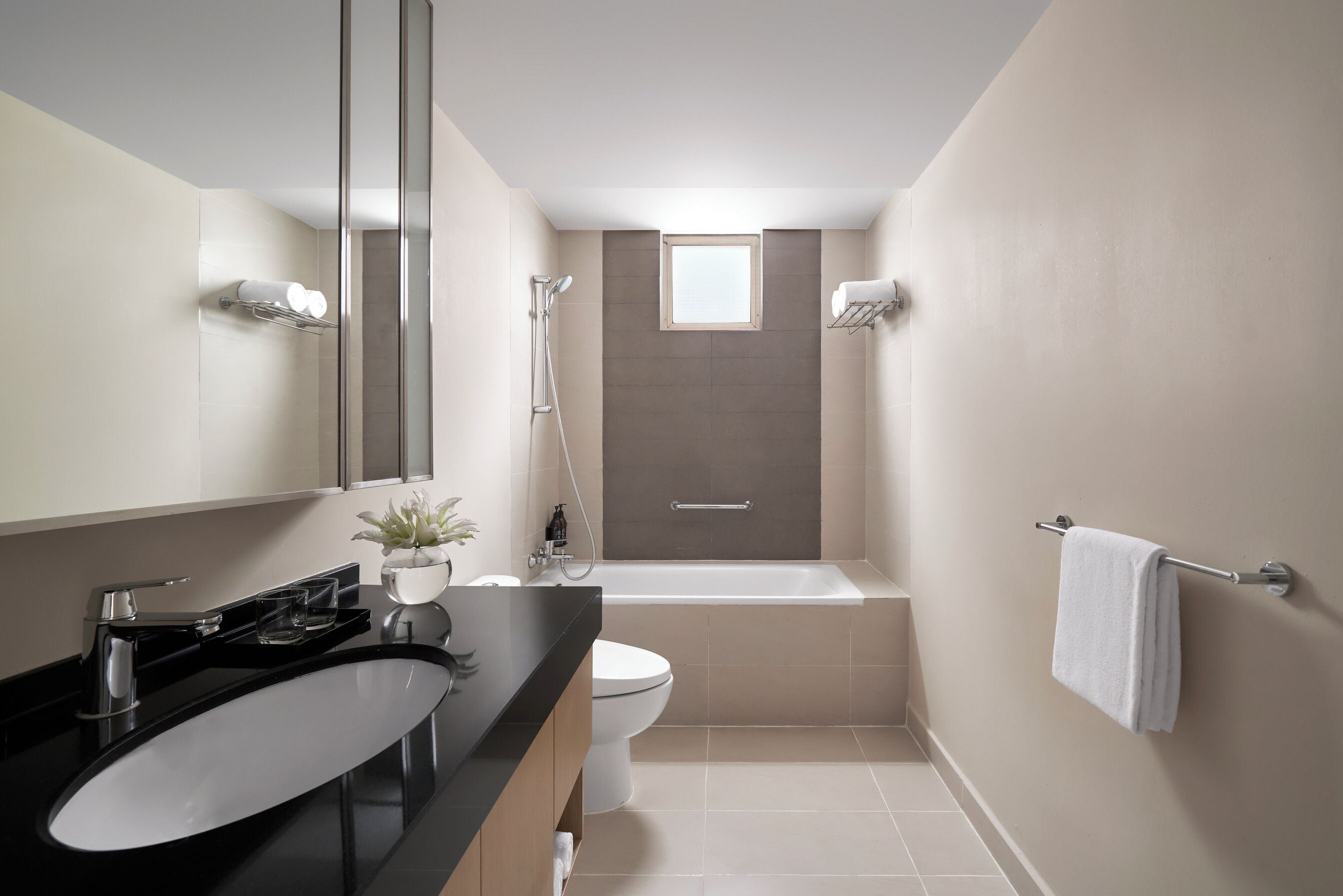Un baño moderno con un lavamanos negro, inodoro blanco y bañera.