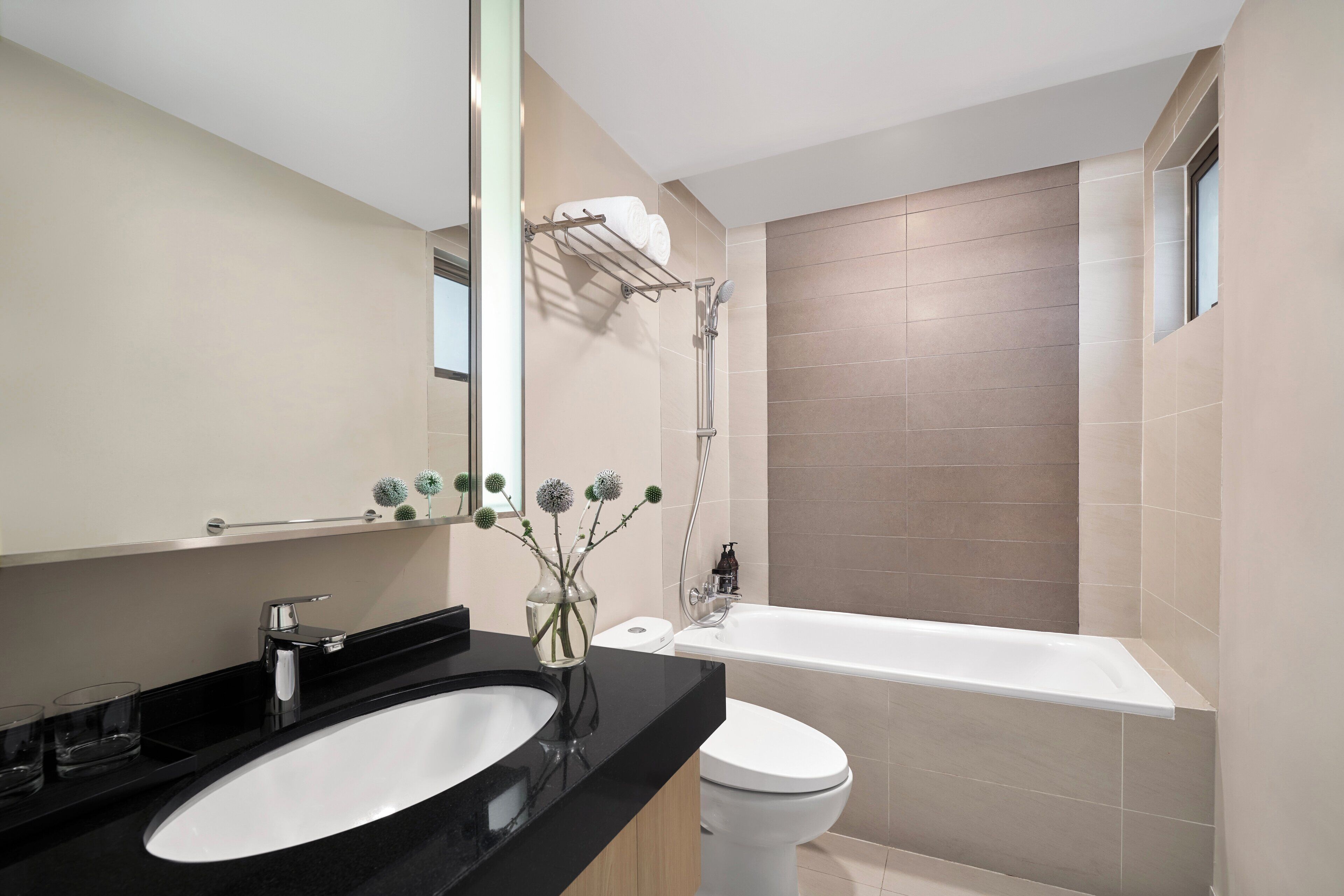 Ein modernes Badezimmer mit einem schwarzen Waschbecken, einer weißen Toilette und einer Badewanne.
