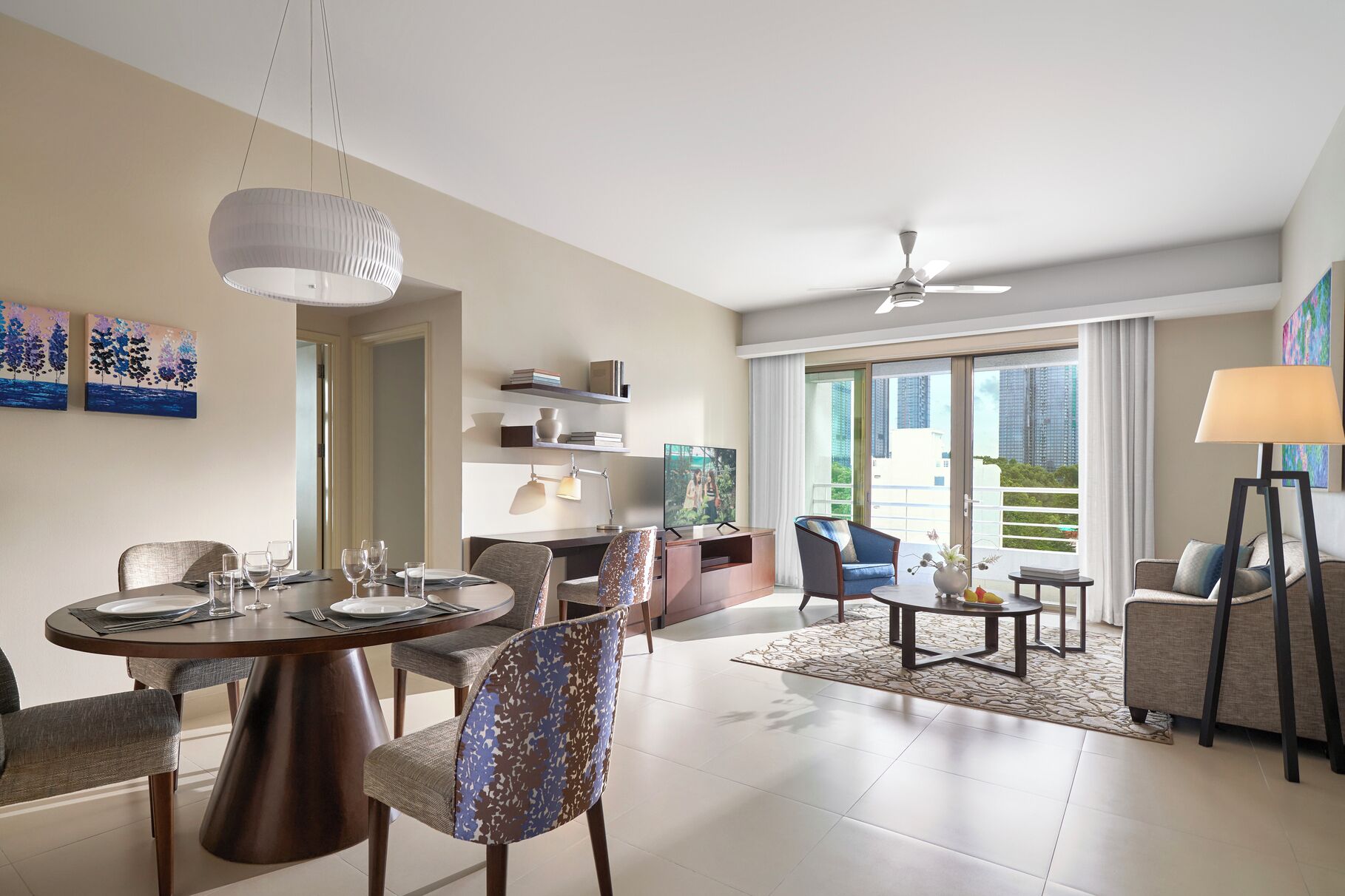 A modern living room with a dining area, a ceiling fan, and a large window with a view of buildings.