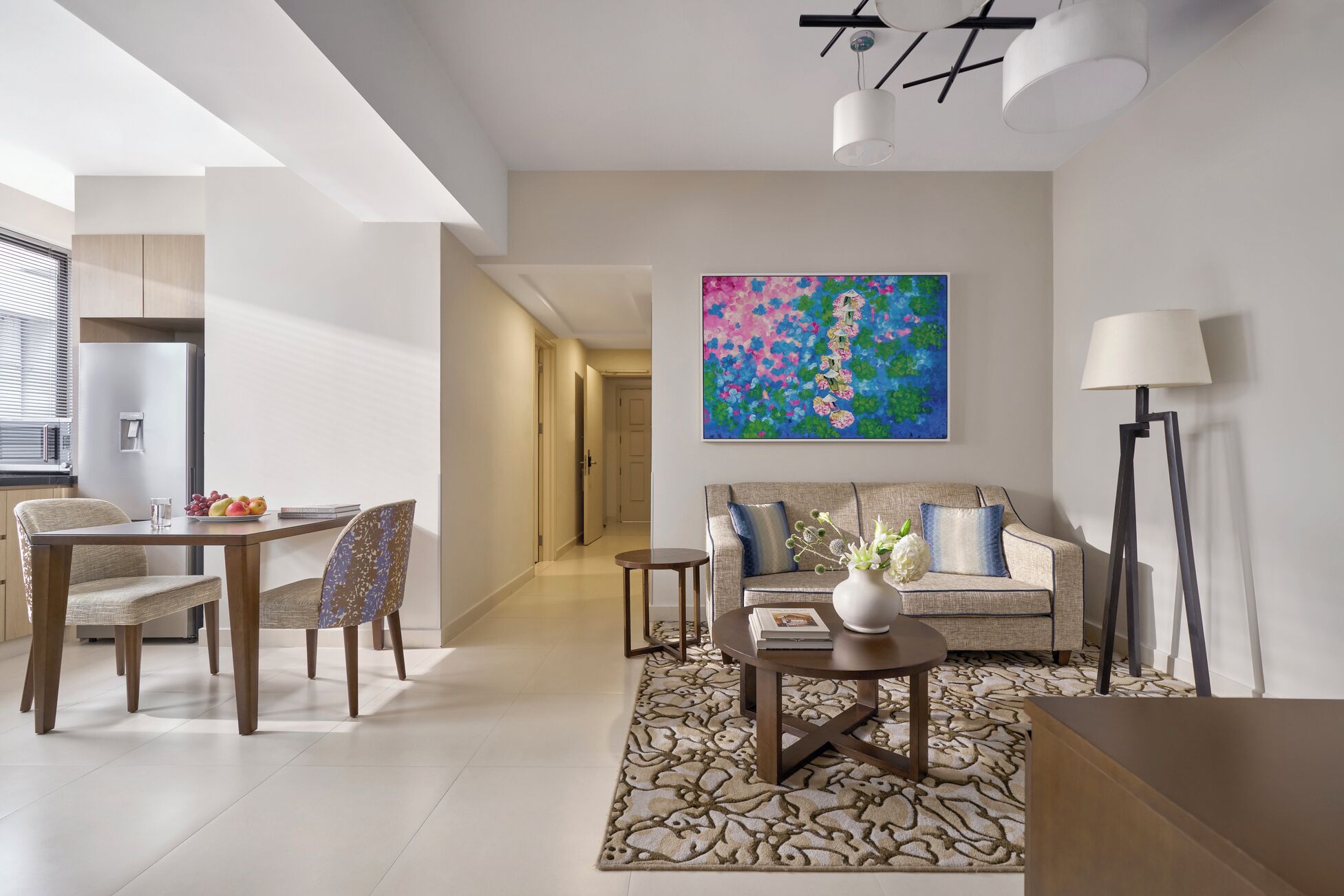 A modern living room with a sofa, coffee table, and a dining area with chairs and a table.