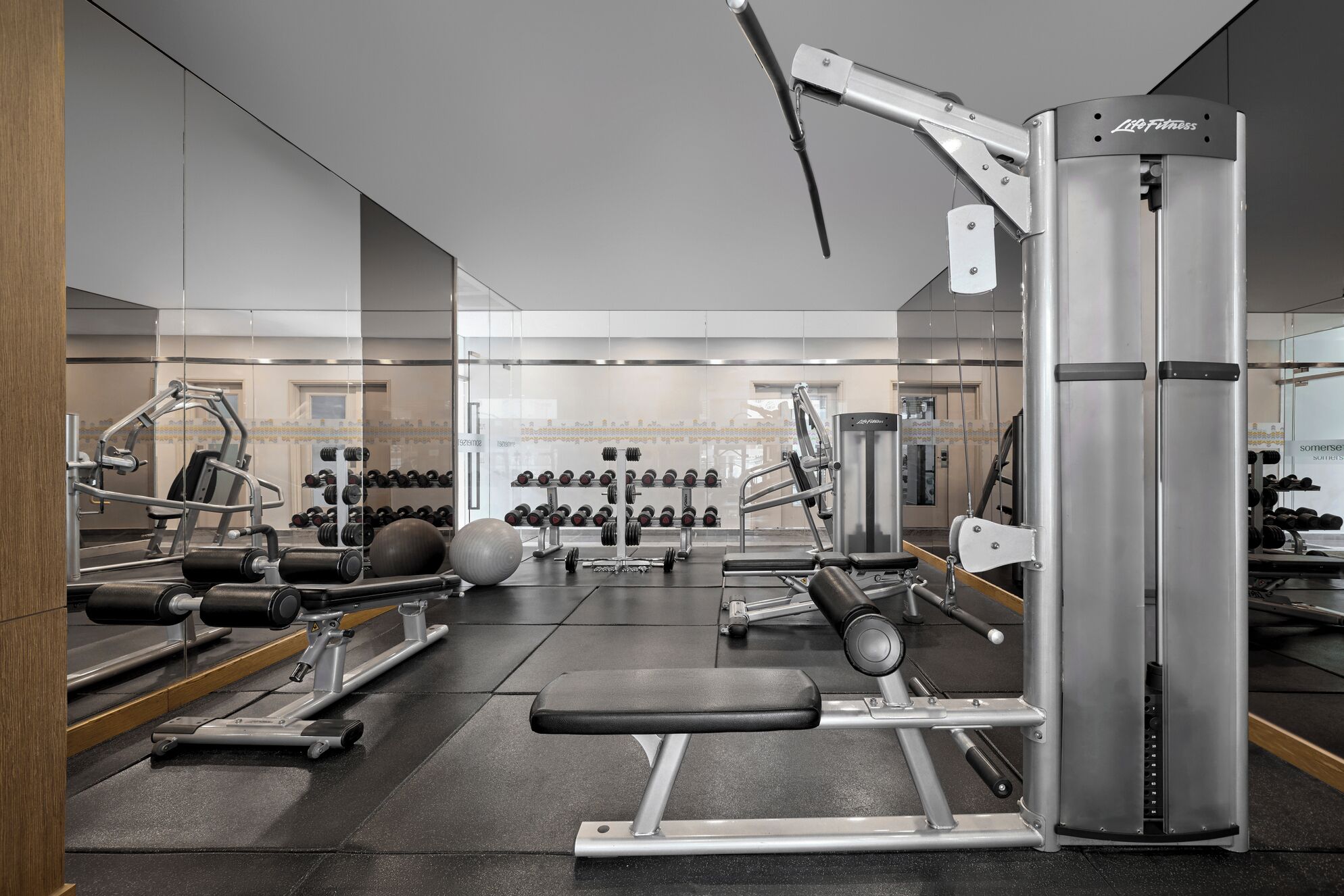 A modern gym with various exercise equipment, including dumbbells, a bench, and weight machines.