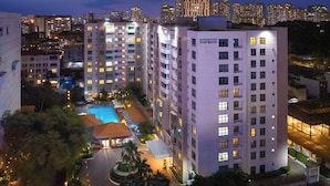 A high-rise hotel with multiple floors, a swimming pool, and a well-lit exterior. - Somerset Ho Chi Minh City (Ho Chi Minh City)