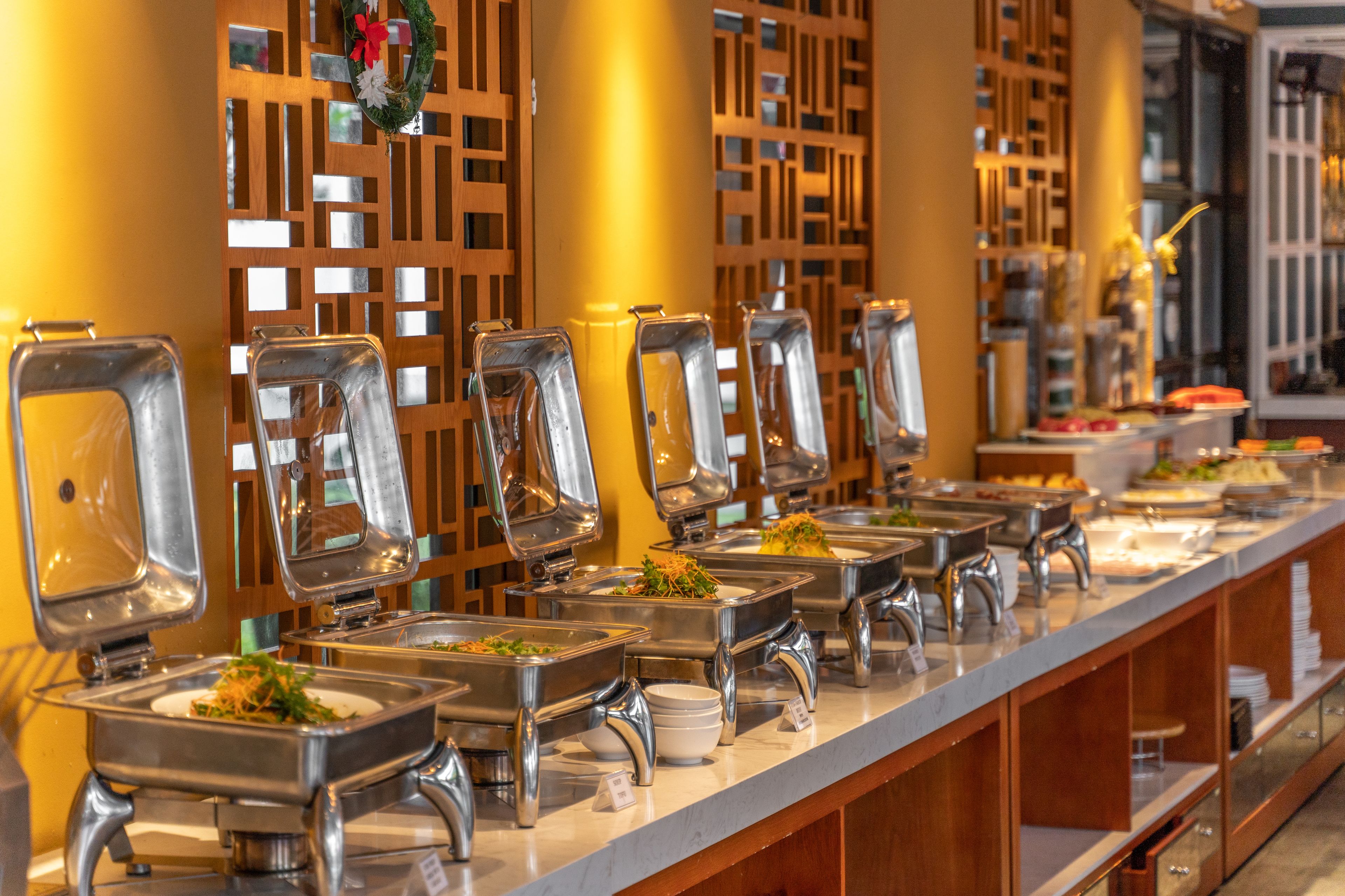 A buffet setup with multiple serving stations, each with a clear glass cover and a metal base.