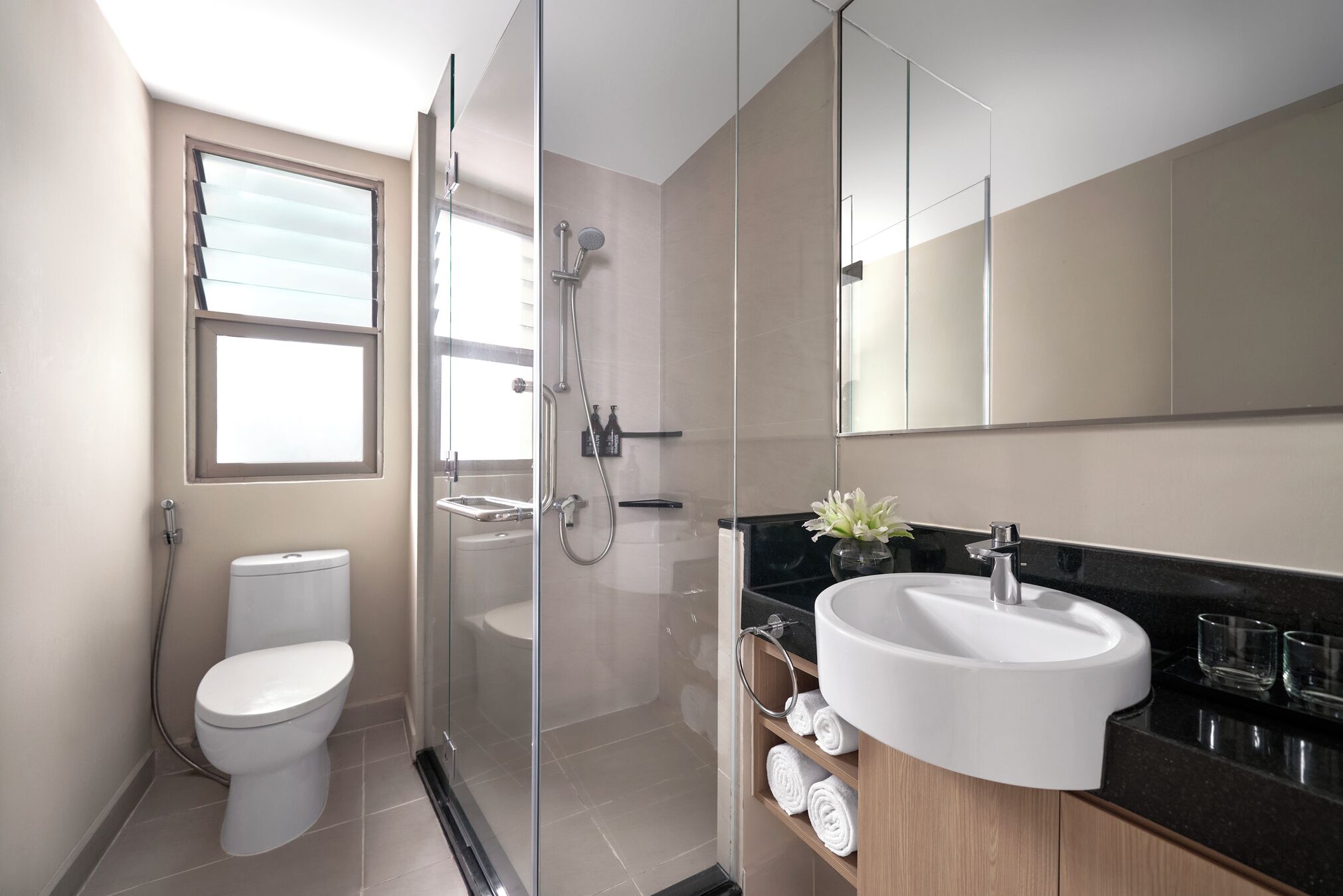 Une salle de bain moderne équipée de toilettes, d’une douche à parois de verre et d’un lavabo avec un miroir au-dessus.