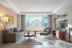 A modern hotel room with a sofa, armchair, coffee table, and TV. - Somerset Chancellor Court Ho Chi Minh City (Ho Chi Minh City)