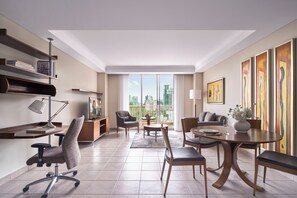 A modern hotel room with a dining area, a desk with a lamp, a chair, a sofa, and artwork on the walls. - Somerset Chancellor Court Ho Chi Minh City (Ho Chi Minh City)