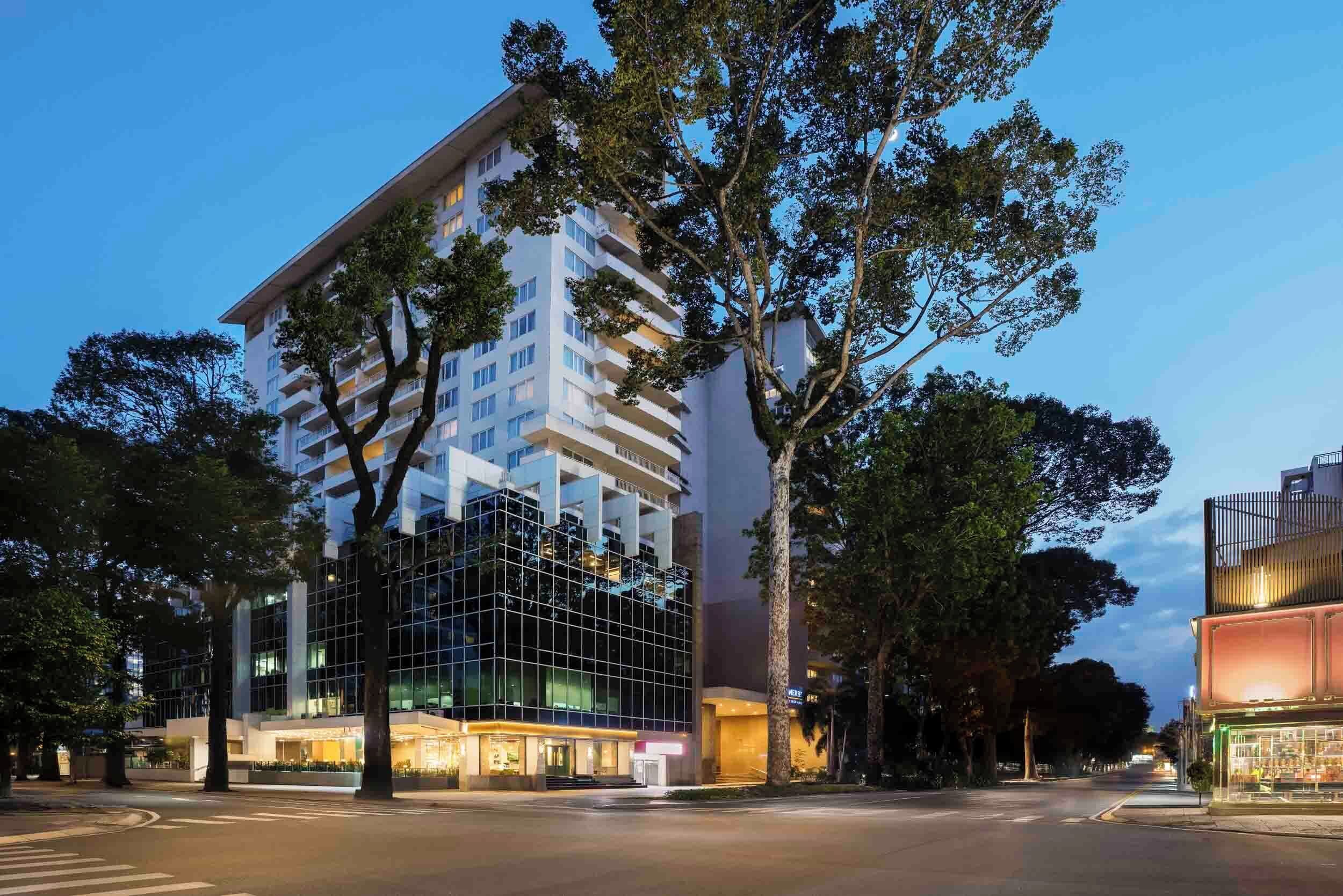 A modern hotel with a glass facade, multiple floors, and a well-lit entrance.
