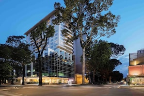 A modern hotel with a glass facade, multiple floors, and a well-lit entrance.
