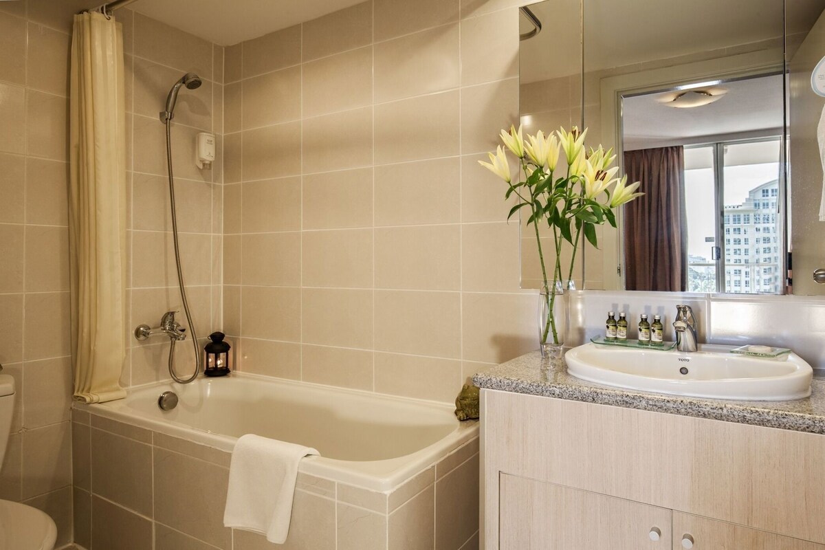 A bathroom with a bathtub, a shower, a toilet, a vanity with a sink, and a mirror.