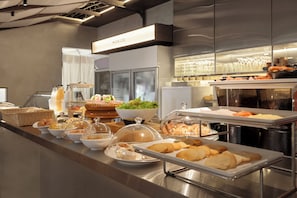 Un buffet proposant divers plats, une vitrine réfrigérée et une enseigne portant l’inscription « MORICO ».