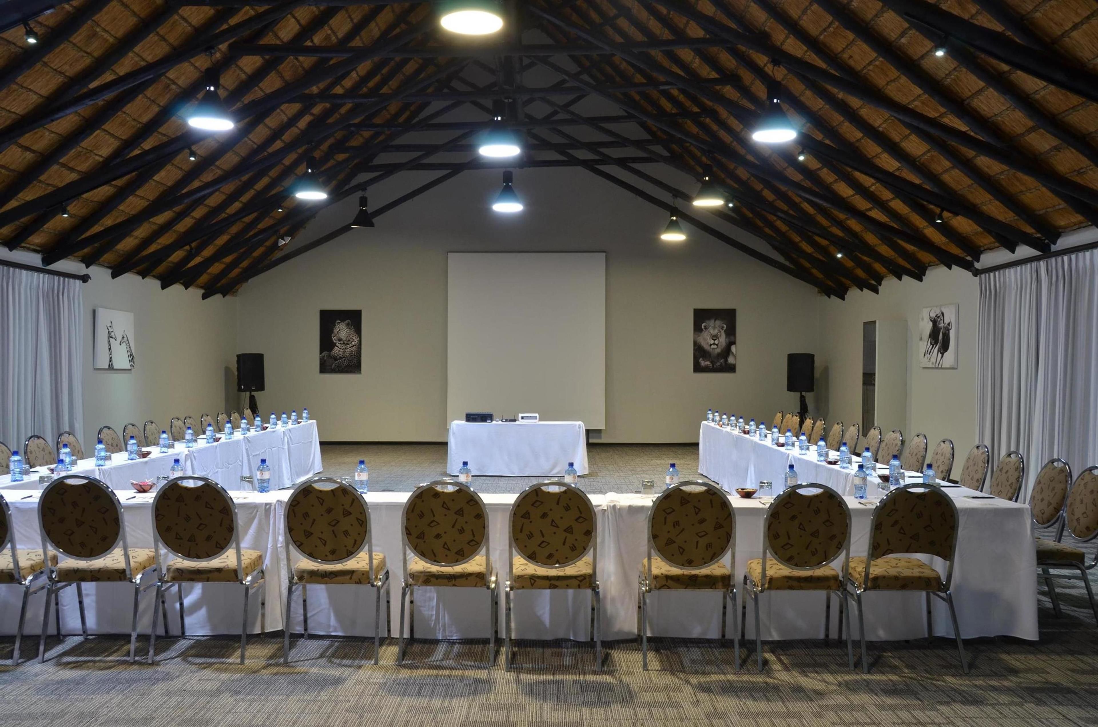 A conference room with a long table, chairs, water bottles, and a projector screen.