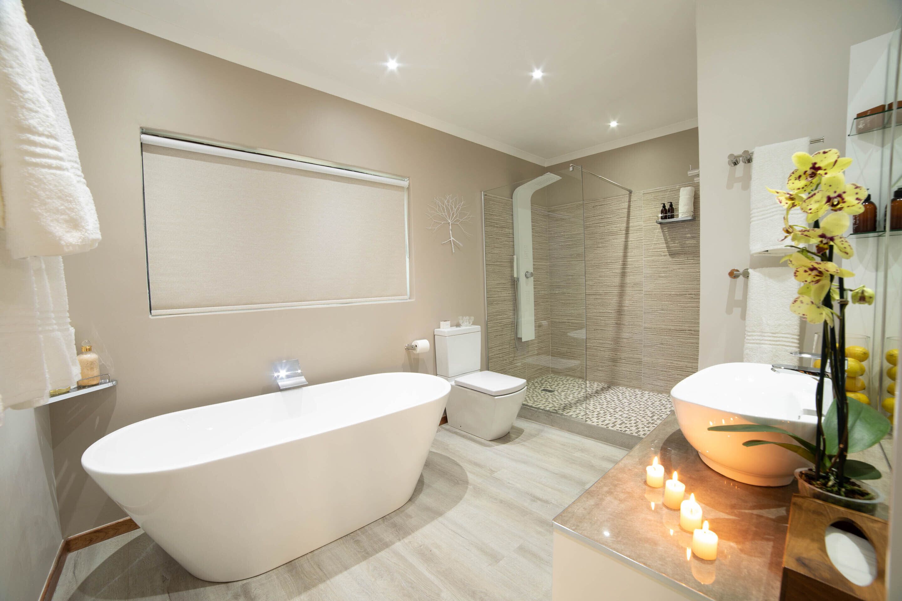 A modern bathroom with a freestanding bathtub, a glass-enclosed shower, and a vanity with a mirror.