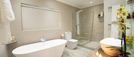 A modern bathroom with a freestanding bathtub, a glass-enclosed shower, and a vanity with a mirror.