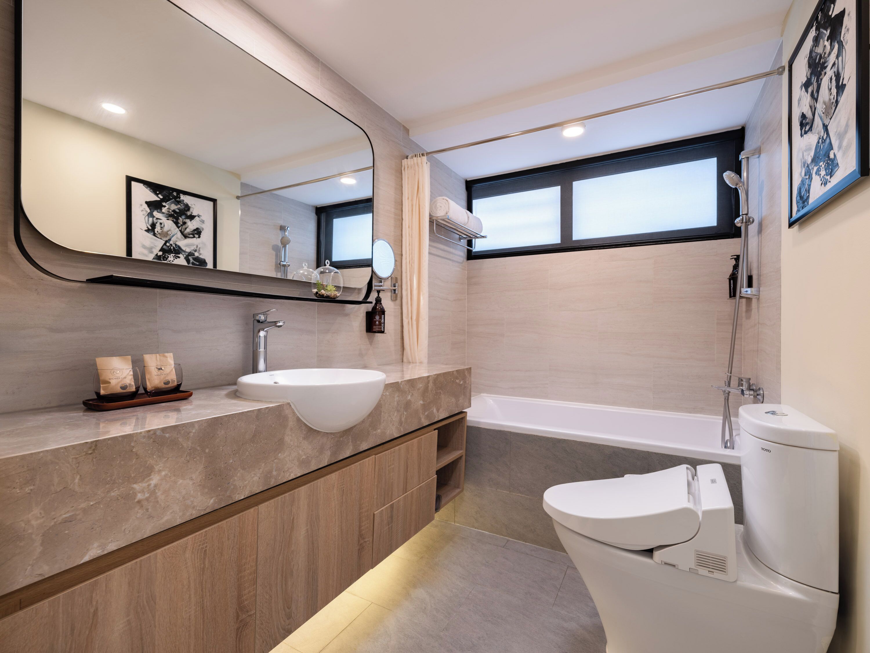 A modern bathroom with a large mirror, a white sink, a bathtub, and a toilet.