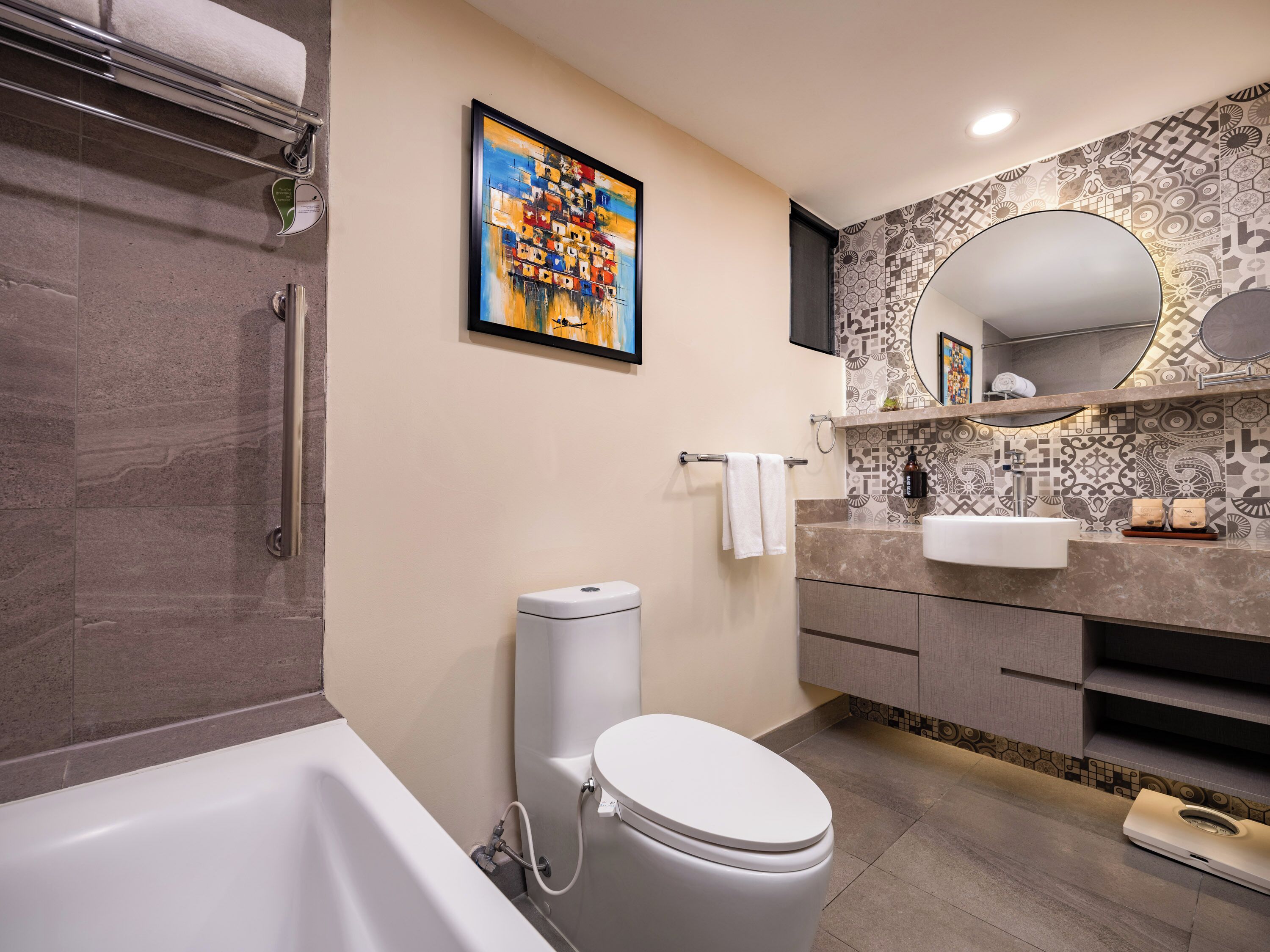 A modern bathroom with a bathtub, toilet, vanity, and a large mirror.