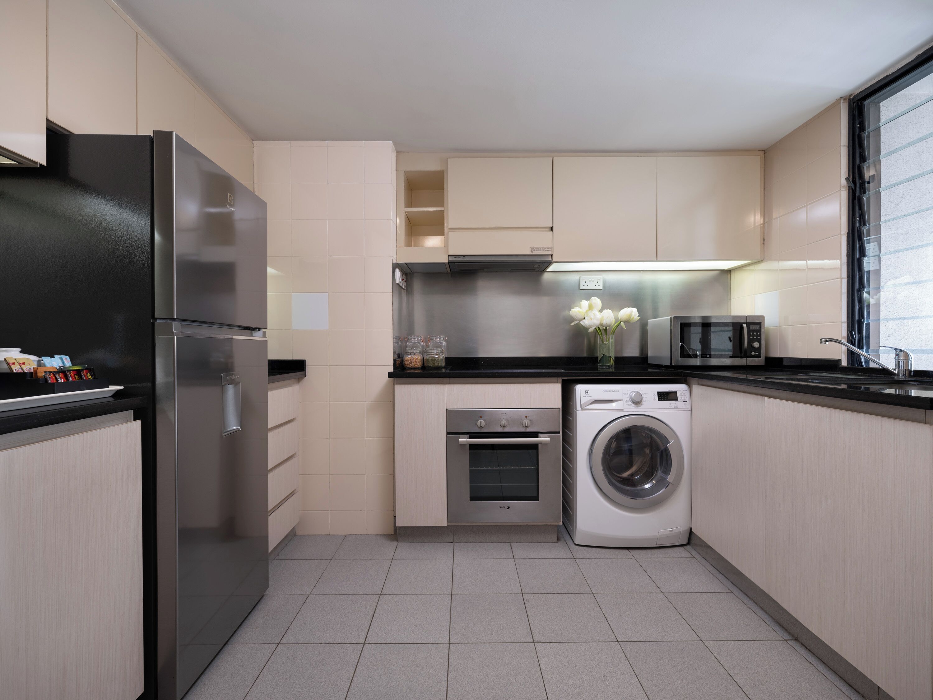 A modern kitchen with a refrigerator, oven, microwave, and washing machine.