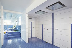 A modern bathroom with white and blue tiles, a shower area, and a set of stairs leading to a balcony.