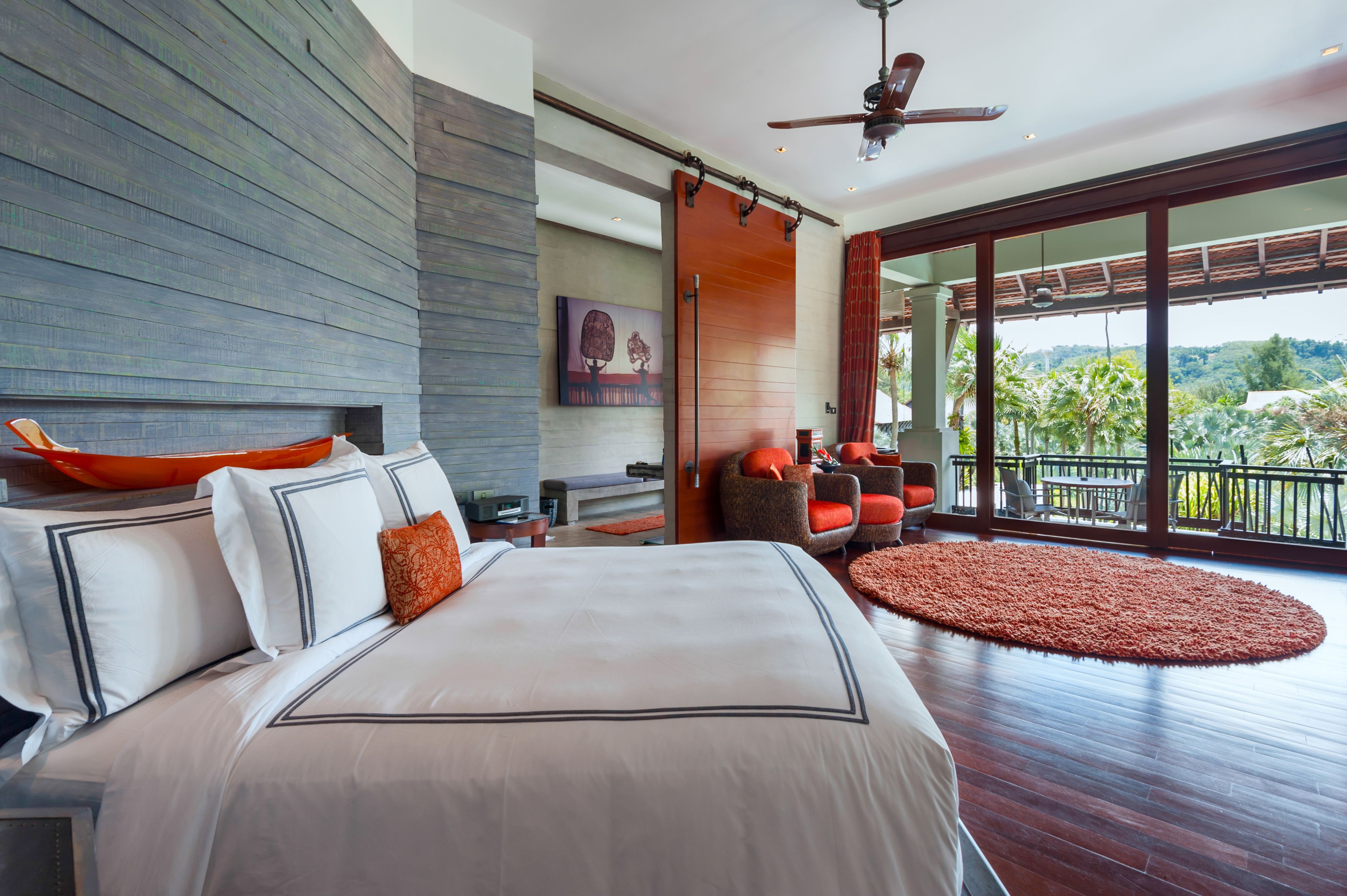 A spacious bedroom with a large bed, a ceiling fan, and a view of the outdoors.