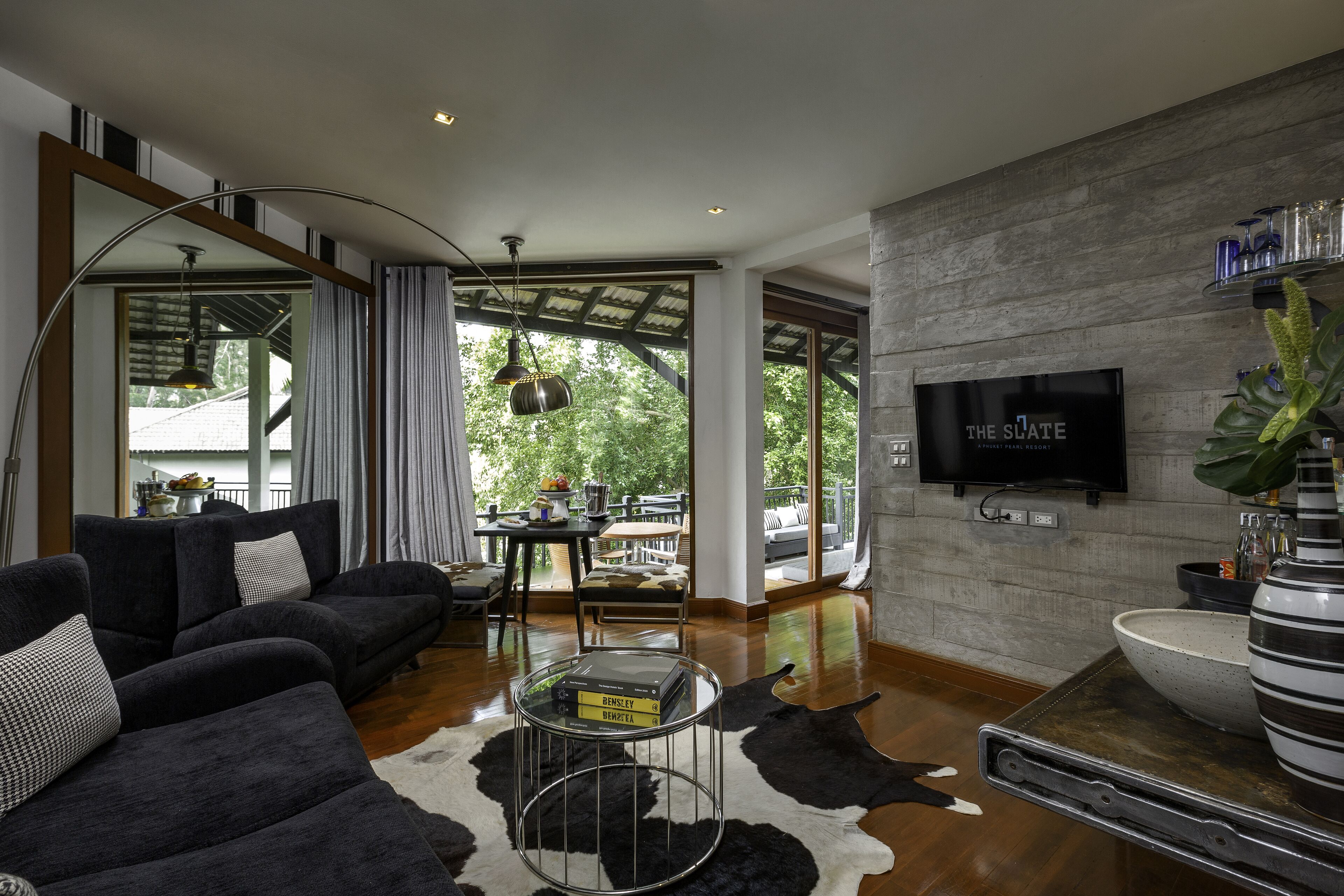A modern living room with a large sofa, a coffee table, and a TV mounted on the wall.