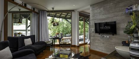 A modern living room with a large sofa, a coffee table, and a TV mounted on the wall.