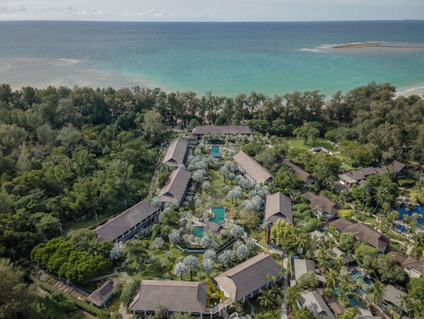 An aerial view of a resort with multiple buildings, a swimming pool, and a beach. - The Slate (Sa Khu)