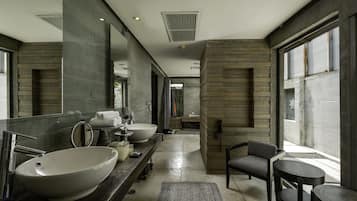 A modern bathroom with a large sink, mirror, and a seating area with a table.