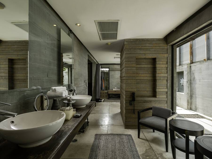 A modern bathroom with a large sink, mirror, and a seating area with a table.
