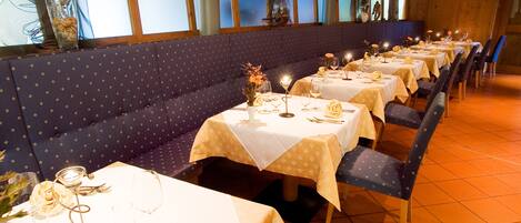A restaurant with multiple tables set for dining, each with a white tablecloth and candle centerpieces.