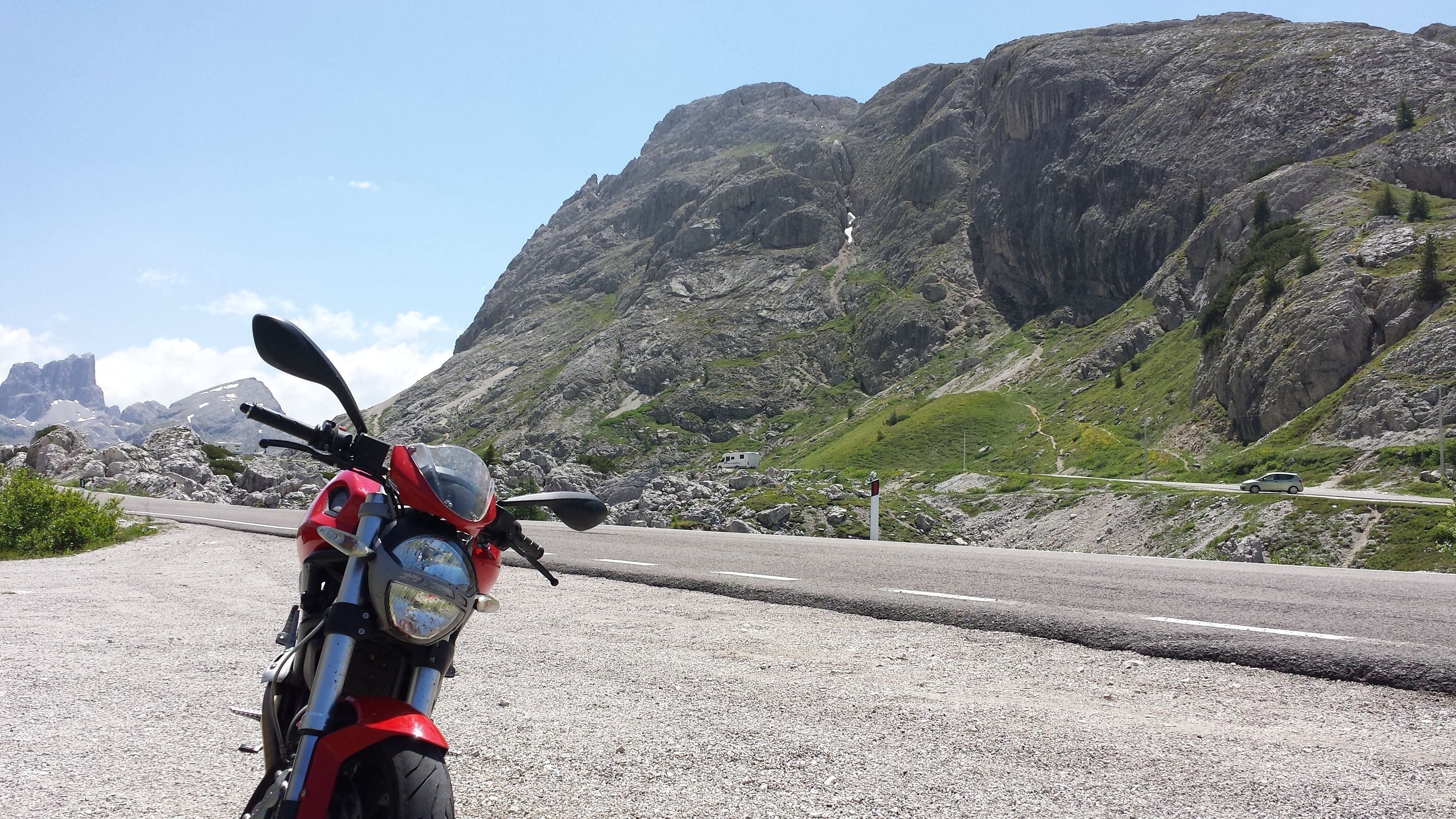 A red motorcycle parked on a gravel road with a mountainous backdrop.